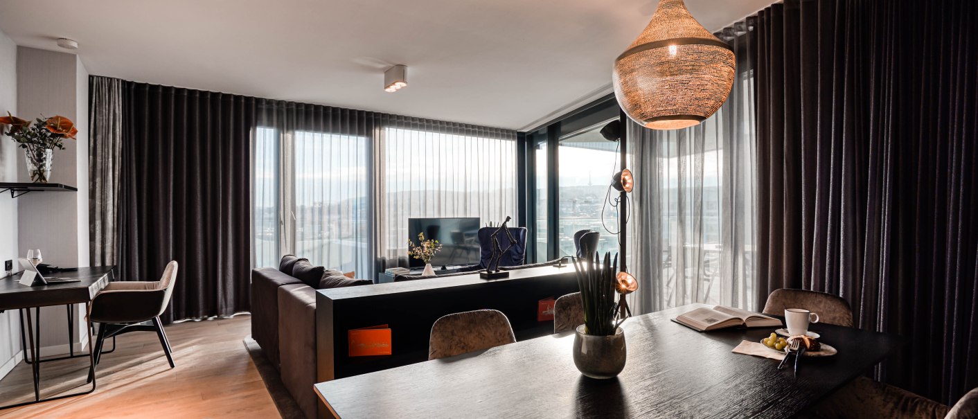 Moderne Suite mit stilvollem Interieur, großem Tisch, Sofa und Panoramafenstern mit Stadtblick. Elegante Beleuchtung und Dekoration., © CLOUD N°7 APARTMENTS GmbH
