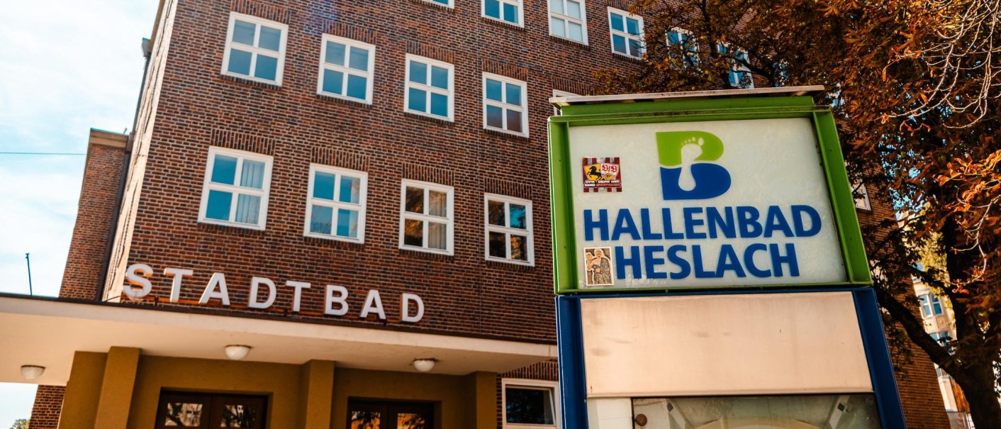 Eingang des Heslacher Hallenbads mit einem Schild und einem Backsteingebäude im Hintergrund. Der Schriftzug 'STADTBAD' ist sichtbar., © Stuttgart Marketing GmbH, Sarah Schmid