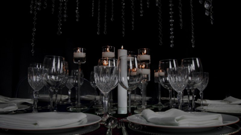 Ein elegant gedeckter Tisch mit Kristallgl&auml;sern, wei&szlig;en Tellern und brennenden Kerzen in einer dunklen Umgebung., &copy; engesser marketing GmbH