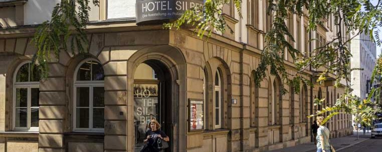 Historic building 'Hotel Silber' on a sunny street corner, with passers-by and trees in the foreground., © Haus der Geschichte Baden-Württemberg