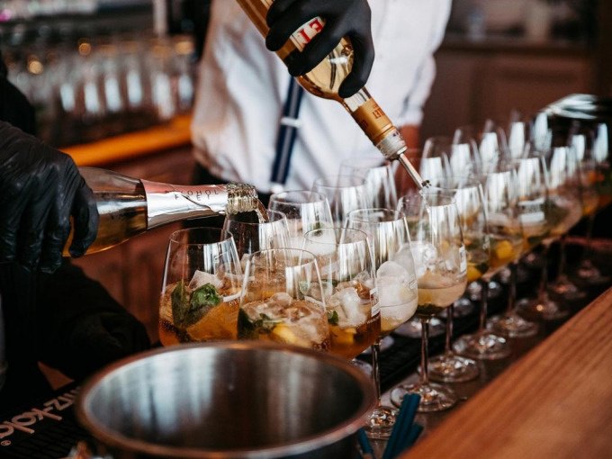 Bartenders in black gloves and white shirts fill several wine glasses with drinks. Ice cubes and mint leaves are in the glasses., © Cool-Tours StattReisen Bartenders in black gloves and white shirts fill several wine glasses with drinks. Ice cubes and mint leaves are in the glasses., © Cool-Tours StattReisen
