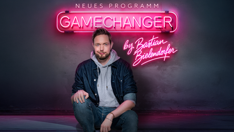 Ein Mann sitzt l&auml;ssig vor einem Neonschild mit der Aufschrift 'GameChanger by Bastian Bielendorfer'., &copy; links im Bild