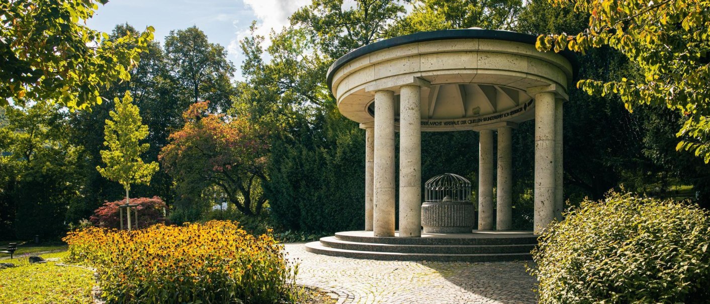 A round pavilion with columns set in a green space, surrounded by trees and flowering plants. The sky is clear and sunny., &copy; SMG Stuttgart Marketing GmbH - Sarah Schmid