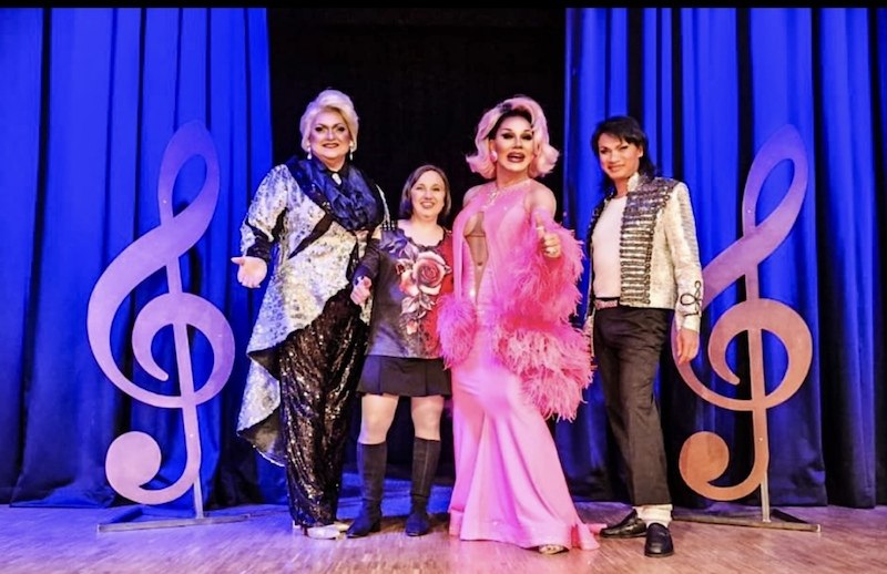 Four people pose on a stage with blue curtains and large clef decorations. They are wearing eye-catching costumes., © Tanja Silzer Events Four people pose on a stage with blue curtains and large clef decorations. They are wearing eye-catching costumes., © Tanja Silzer Events