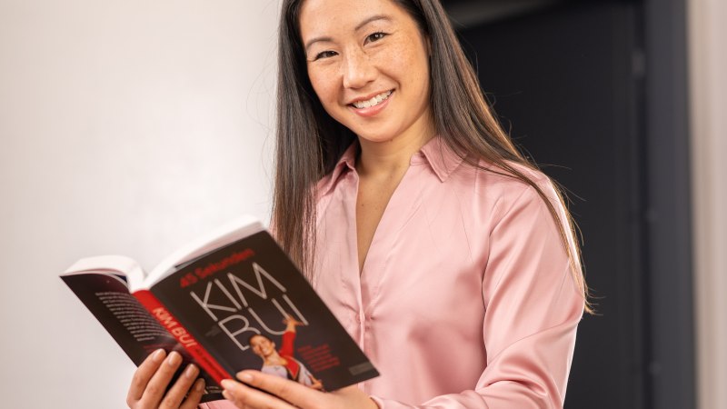 Eine Person in rosa Bluse liest lächelnd ein Buch mit dem Titel '45 Sekunden. Kim Bui'., © Kim Bui Eine Person in rosa Bluse liest lächelnd ein Buch mit dem Titel '45 Sekunden. Kim Bui'., © Kim Bui