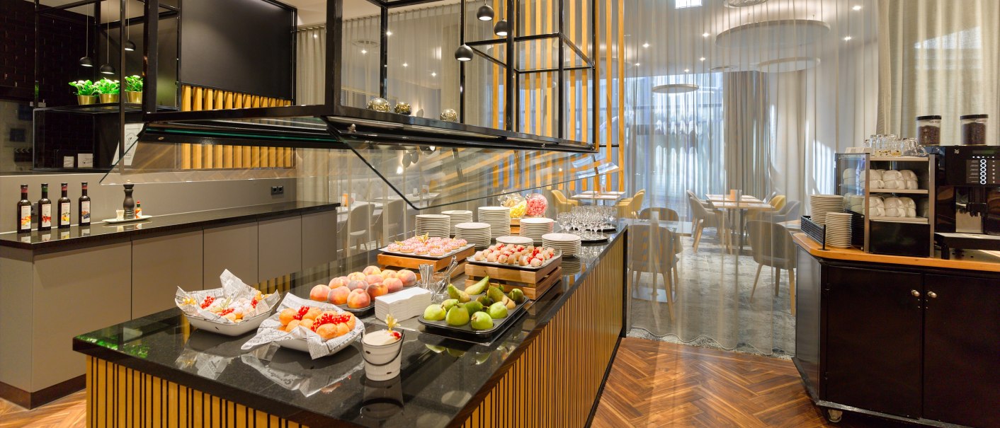 Elegant buffet with fruit and drinks in a modern restaurant with wooden floors and stylish furnishings., © Holiday Inn Stuttgart Elegant buffet with fruit and drinks in a modern restaurant with wooden floors and stylish furnishings., © Holiday Inn Stuttgart