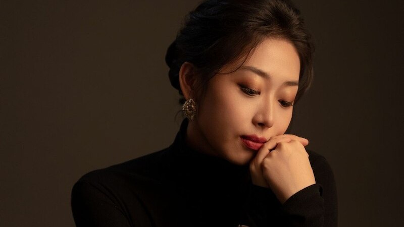 Eine Frau in einem schwarzen Rollkragenpullover schaut nachdenklich zur Seite, die Hand am Kinn gest&uuml;tzt. Sie tr&auml;gt auff&auml;llige Ohrringe., &copy; il Gusto Barocco - Stuttgarter Barockorchester