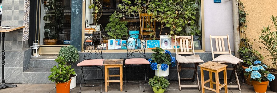 Ein gem&uuml;tliches Au&szlig;encaf&eacute; mit Pflanzen, B&uuml;chern im Fenster und mehreren St&uuml;hlen vor der Fassade., &copy; Caf&eacute; Che