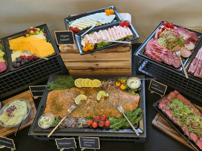 Ein reichhaltiges Buffet mit Lachs, Aufschnitt, Käse und veganen Optionen, dekoriert mit frischen Kräutern und Zitronenscheiben., © Cool-Tours StattReisen Ein reichhaltiges Buffet mit Lachs, Aufschnitt, Käse und veganen Optionen, dekoriert mit frischen Kräutern und Zitronenscheiben., © Cool-Tours StattReisen