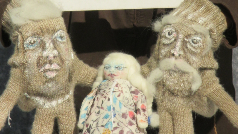 Drei gestrickte Puppen mit weißen Haaren und blauen Augen. Zwei größere Puppen halten eine kleinere Puppe in der Mitte., © Figurentheater Weidringer Drei gestrickte Puppen mit weißen Haaren und blauen Augen. Zwei größere Puppen halten eine kleinere Puppe in der Mitte., © Figurentheater Weidringer