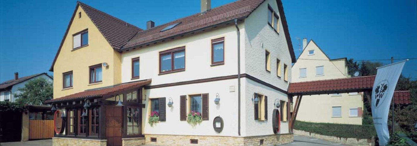 Zweist&ouml;ckiges Geb&auml;ude mit gelber und wei&szlig;er Fassade, roten Dachziegeln. Ein VdW-Banner steht davor. Klare, blaue Himmel im Hintergrund., &copy; Weinstube J&auml;gerhof