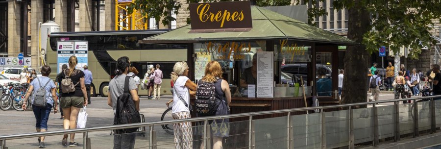 Ein Crêpes-Stand am Stuttgarter Hauptbahnhof mit mehreren Menschen, die anstehen. Im Hintergrund sind Fahrräder und ein Bus zu sehen., © SMG, Sarah Schmid Ein Crêpes-Stand am Stuttgarter Hauptbahnhof mit mehreren Menschen, die anstehen. Im Hintergrund sind Fahrräder und ein Bus zu sehen., © SMG, Sarah Schmid