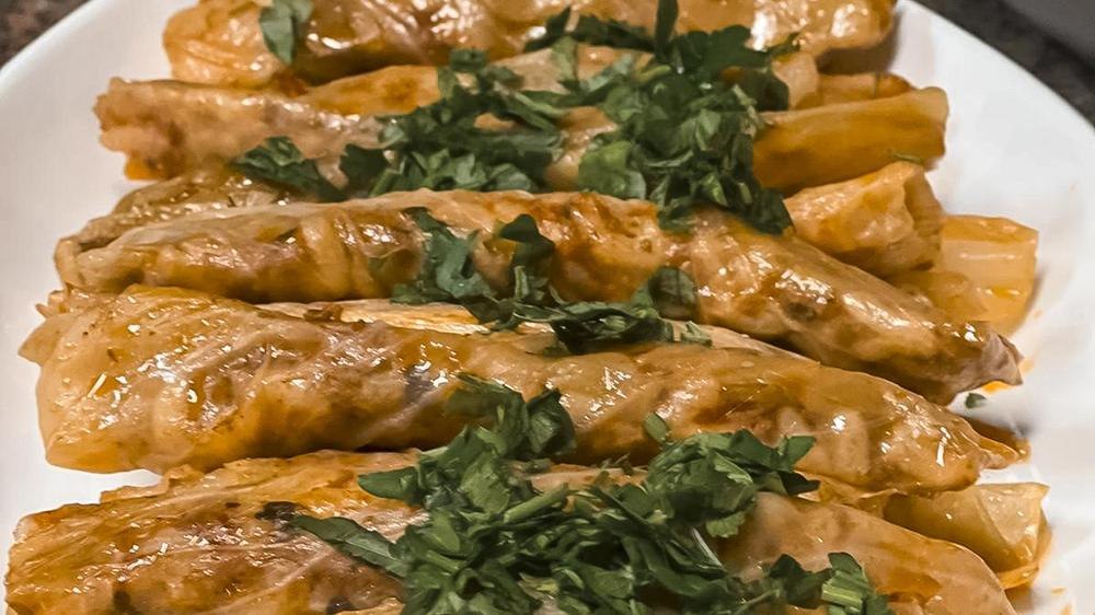 Gefüllte Kohlrouladen auf einem Teller, garniert mit frischen Kräutern. Sie sind goldbraun und appetitlich angerichtet., © Zauberküche, Stuttgart