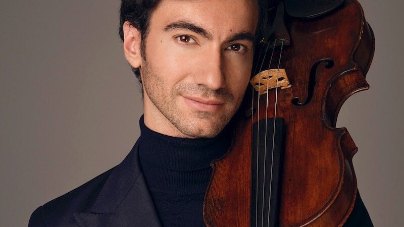 Ein Mann in dunklem Anzug h&auml;lt eine Geige an seine Schulter und l&auml;chelt leicht. Der Hintergrund ist neutral gehalten., &copy; Klassische Philharmonie Bonn e.V.