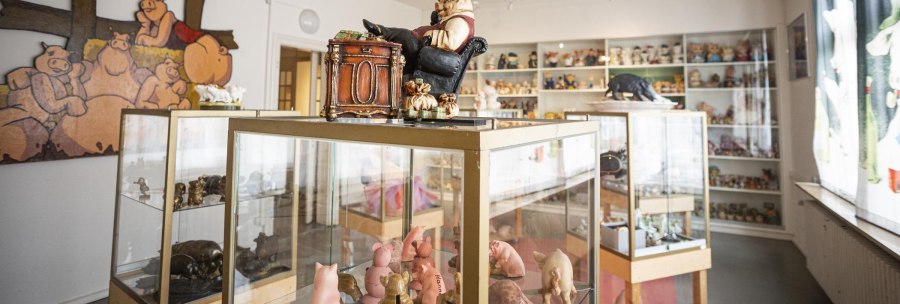 A room in the Stuttgart Pig Museum with showcases full of pig figures and a large mural of pigs., © Stuttgart-Marketing GmbH, Sarah Schmid