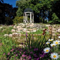 Ein blühender Garten mit bunten Blumen, einem kleinen Teich und einem Pavillon im Hintergrund, umgeben von Bäumen., © Staatsministerium Baden-Württemberg