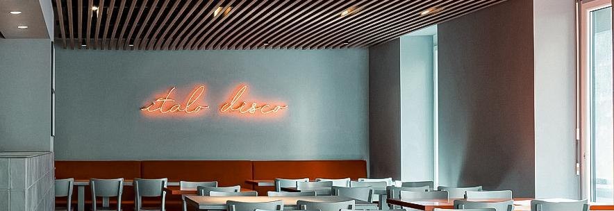 Modern restaurant with gray chairs, wooden lattice ceiling and neon 'Italo Disco' lettering on the wall., © Italo Disco, Stuttgart Modern restaurant with gray chairs, wooden lattice ceiling and neon 'Italo Disco' lettering on the wall., © Italo Disco, Stuttgart