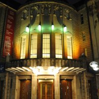 The Altes Schauspielhaus at night, illuminated with colorful lights. The entrance is surrounded by historic buildings., © Schauspielbühnen Stuttgart
