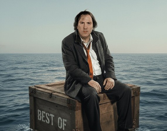 Ein Mann in Anzug und Krawatte sitzt auf einer Holzkiste mit der Aufschrift 'Best Of', die auf dem Meer schwimmt. Der Himmel ist klar und blau., &copy; Rosenau Kultur e.V.