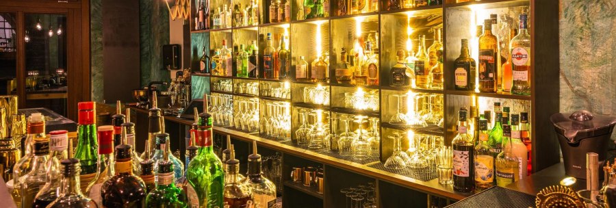 A stylish bar with illuminated shelves filled with various bottles and glasses. The atmosphere is warm and inviting., © Holzmaler, Stuttgart
