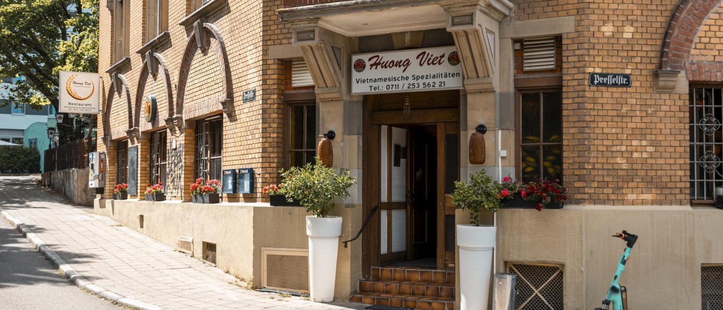 Eingang des Restaurants Huong Viet mit Blumenarrangements und einem E-Scooter auf dem Gehweg., © Stuttgart Marketing GmbH, Sarah Schmid