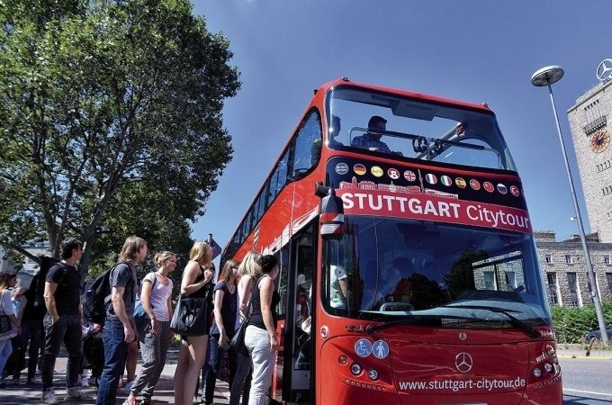 Roter Doppeldeckerbus der Stuttgart Citytour, Menschen steigen ein. Der Bus steht an einer Haltestelle, im Hintergrund Bäume und ein Gebäude., © SMG, Pierre Polak Roter Doppeldeckerbus der Stuttgart Citytour, Menschen steigen ein. Der Bus steht an einer Haltestelle, im Hintergrund Bäume und ein Gebäude., © SMG, Pierre Polak