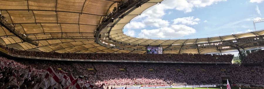 Die Mercedes-Benz Arena in Stuttgart, voll besetzt mit Fans, die Fahnen schwenken. Das Stadiondach ist gut sichtbar, der Himmel ist blau mit Wolken., &copy; Stuttgart-Marketing GmbH