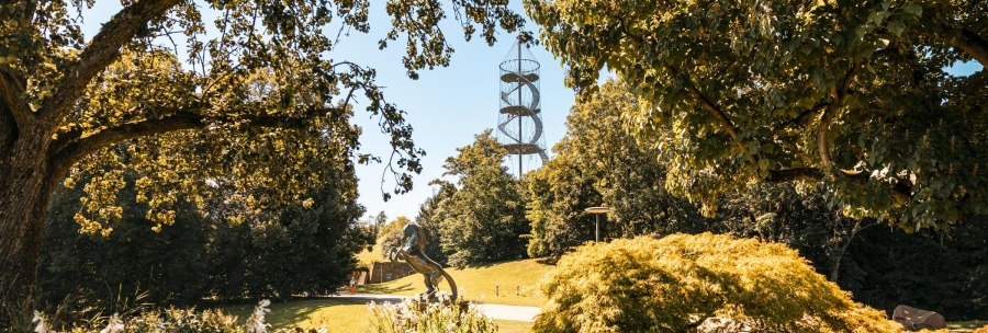 A green park with trees, a horse sculpture and a spiral-shaped observation tower in the background., © SMG Stuttgart Marketing GmbH - Sarah Schmid A green park with trees, a horse sculpture and a spiral-shaped observation tower in the background., © SMG Stuttgart Marketing GmbH - Sarah Schmid