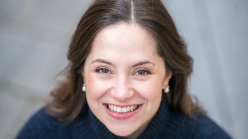 Nahaufnahme einer lächelnden Frau mit braunen Haaren und Perlenohrringen, die in die Kamera schaut., © Giorgia Cappello