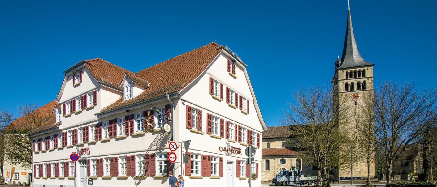 A historic building with red shutters in Sindelfingen's old town. In the background, a church tower can be seen rising into the blue sky., © SMG Stuttgart Marketing GmbH - Sarah Schmid A historic building with red shutters in Sindelfingen's old town. In the background, a church tower can be seen rising into the blue sky., © SMG Stuttgart Marketing GmbH - Sarah Schmid