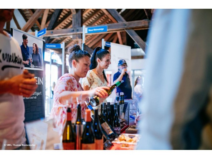 Zwei Frauen schenken Wein bei einer Veranstaltung ein. Im Hintergrund sind Werbebanner und Weinflaschen zu sehen., © Stuttgart-Marketing GmbH, Thomas Niedermüller Zwei Frauen schenken Wein bei einer Veranstaltung ein. Im Hintergrund sind Werbebanner und Weinflaschen zu sehen., © Stuttgart-Marketing GmbH, Thomas Niedermüller