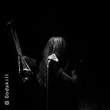 Musiker mit langem Haar hält Mikrofon auf dunkler Bühne, schwarz-weiß., © links im Bild Musiker mit langem Haar hält Mikrofon auf dunkler Bühne, schwarz-weiß., © links im Bild