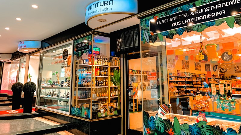 Ein Feinkostladen namens Ventura bietet lateinamerikanische Lebensmittel und Kunsthandwerk an. Das Schaufenster ist bunt dekoriert., © Feinkost Latino Ventura