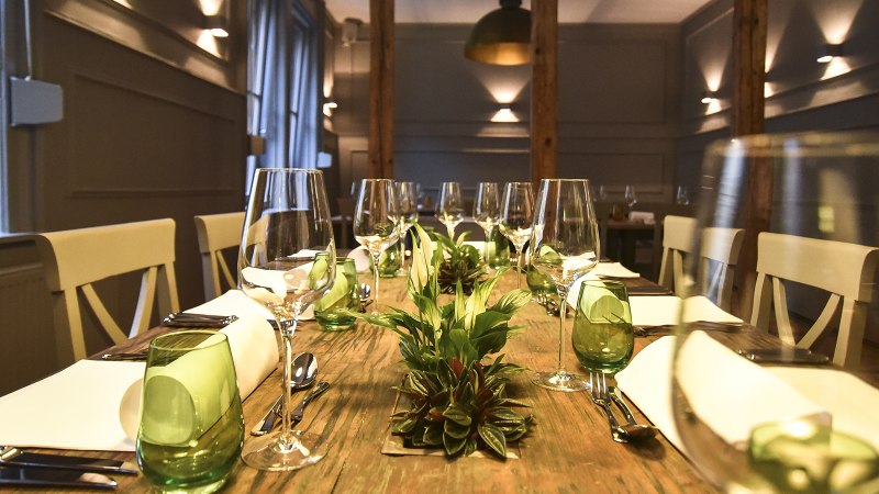 A stylishly laid dining table with wine glasses, green glasses and plants as decoration in an elegant room., &copy; Classic Rock Caf&eacute; Gastronomie- Betriebs GmbH