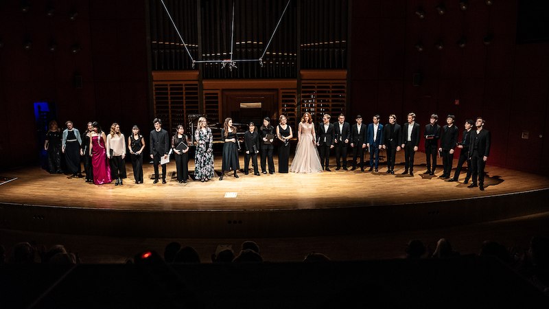 Eine Gruppe von Menschen steht auf einer B&uuml;hne in einem Konzertsaal. Sie sind elegant gekleidet und stehen vor einer gro&szlig;en Orgel., &copy; Staatliche Hochschule f&uuml;r Musik und Darstellende Kunst