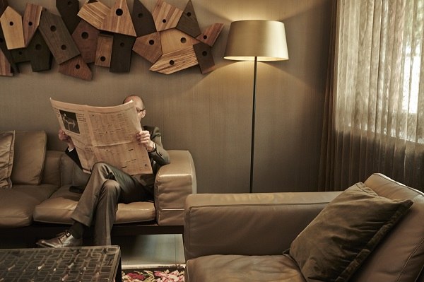 A man is sitting in the lobby of the Waldhotel Stuttgart reading a newspaper. The furnishings are modern with leather sofas and stylish wall decorations., &copy; Waldhotel Stuttgart GmbH
