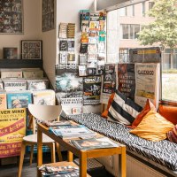 Ein Plattenladen mit Vinyls, Postern und einer gemütlichen Sitzecke mit Kissen. Große Fensterfront mit Blick nach draußen., © SMG, Sarah Schmid Ein Plattenladen mit Vinyls, Postern und einer gemütlichen Sitzecke mit Kissen. Große Fensterfront mit Blick nach draußen., © SMG, Sarah Schmid