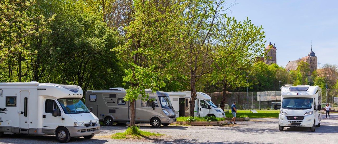 Motorhome site in Besigheim with several motorhomes under green trees, a church visible in the background., © Boris Lehner Motorhome site in Besigheim with several motorhomes under green trees, a church visible in the background., © Boris Lehner