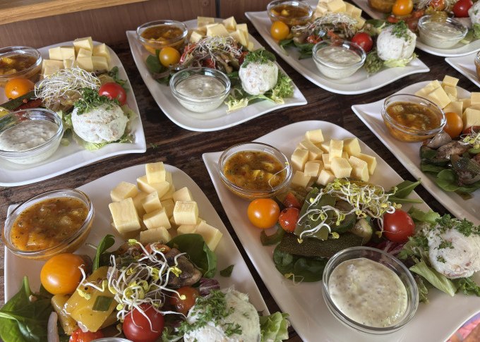 Teller mit Tapas: Käsewürfel, Tomaten, Saucen und Salat auf einem Holztisch arrangiert., © Cool-Tours StattReisen