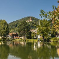 The lake in Bad Liebenzell reflects the surrounding houses. In the background, a castle can be seen on a wooded hill., © SMG Stuttgart Marketing GmbH - Sarah Schmid The lake in Bad Liebenzell reflects the surrounding houses. In the background, a castle can be seen on a wooded hill., © SMG Stuttgart Marketing GmbH - Sarah Schmid