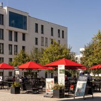Moderne Wohngeb&auml;ude in Stuttgart Killesbergh&ouml;he, mit roten Sonnenschirmen und Menschen auf einem Platz bei sonnigem Wetter., &copy; Stuttgart-Marketing GmbH, Sarah Schmid