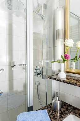 Modernes Badezimmer mit Glasdusche, Handtuch, Blumen in Vase und Spiegel. Weiße Fliesen und Granitoberfläche., © Hotel Adler Waiblingen Modernes Badezimmer mit Glasdusche, Handtuch, Blumen in Vase und Spiegel. Weiße Fliesen und Granitoberfläche., © Hotel Adler Waiblingen
