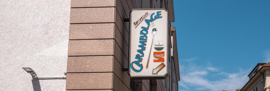 Ein Schild mit der Aufschrift 'Carambolage' h&auml;ngt an einer Geb&auml;udewand. Der Himmel ist klar und blau., &copy; SMG, Sarah Schmid
