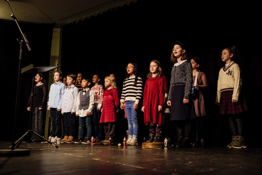 Ein Kinderchor steht auf einer Bühne und singt vor einem Mikrofon. Die Kinder tragen festliche Kleidung., © Foto: Thomas Neumayer Ein Kinderchor steht auf einer Bühne und singt vor einem Mikrofon. Die Kinder tragen festliche Kleidung., © Foto: Thomas Neumayer