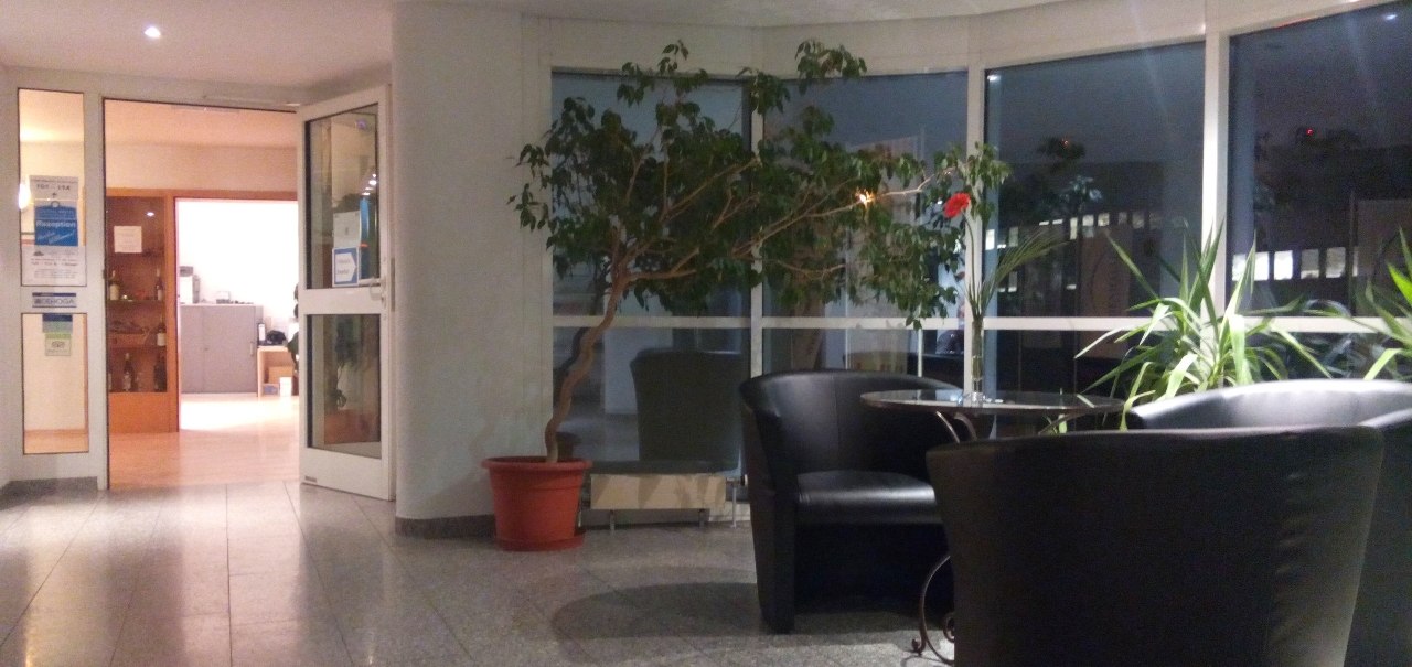 Lobby im 1. OG mit Pflanzen, runden Sesseln und einem kleinen Tisch. Gro&szlig;e Fenster im Hintergrund, Eingangst&uuml;r links., &copy; Central Hotel