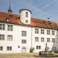 The courtyard of Waldenbuch Castle features white buildings with red roofs and a central fountain. A blue sky completes the scene., &copy; SMG Stuttgart Marketing GmbH - Sarah Schmid