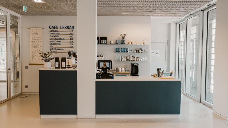Modernes Café mit Tresen, Preistafel und Regalen in der Stadtbibliothek Stuttgart. Helle, einladende Atmosphäre im 8. Obergeschoss., © sina fotografie, Café Lesbar, Stuttgart