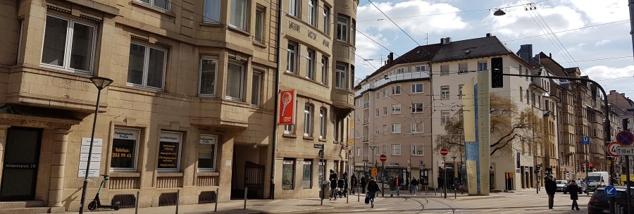 Urban street scene with historic buildings, streetcar tracks and pedestrians. An e-scooter stands on a lamppost., &copy; SMG