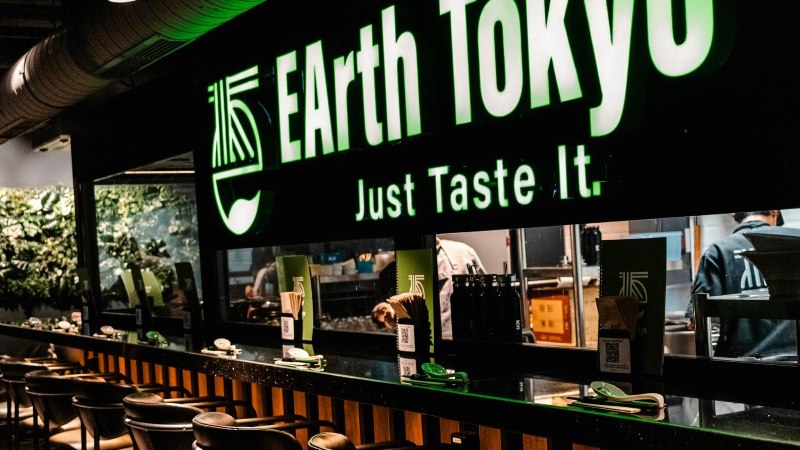 Restaurant mit dem Schild 'EArth Tokyo' und dem Slogan 'Just Taste It'. Moderne Einrichtung mit Pflanzenwand und Theke., © Stuttgart Marketing GmbH - Sarah Schmid