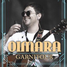 Ein Musiker mit Sonnenbrille und Gitarre lächelt. Text: Oimara Garnitour., © links im Bild